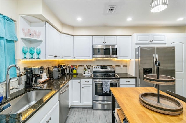 kitchen featuring tasteful backsplash, sink, white cabinets, stainless steel appliances, and light wood-type flooring