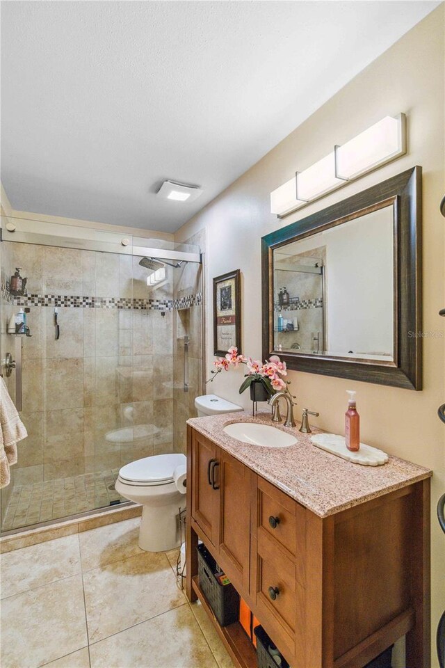 bathroom featuring walk in shower, vanity, tile patterned floors, and toilet