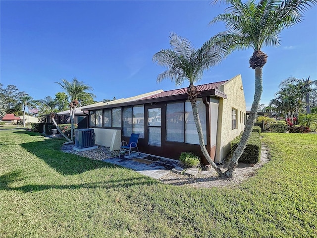 rear view of property featuring a yard, central AC, and a sunroom