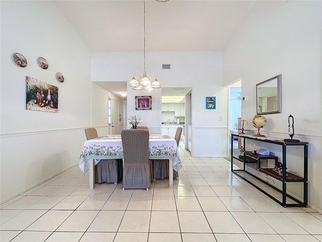 dining space featuring a high ceiling, light tile patterned floors, and an inviting chandelier