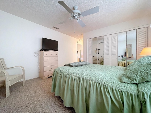 carpeted bedroom featuring ceiling fan, a closet, and a textured ceiling