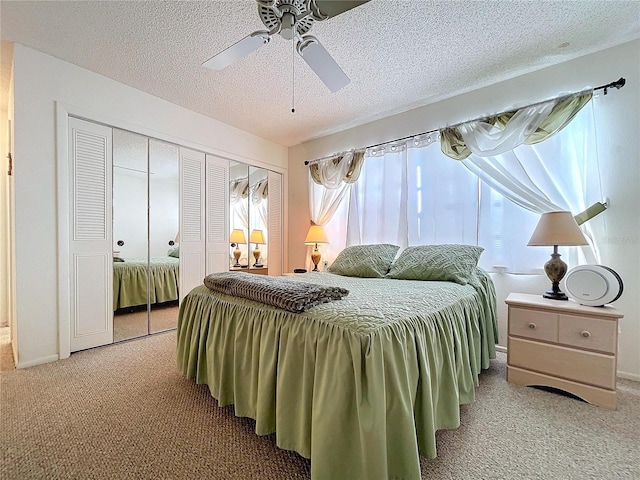 carpeted bedroom with ceiling fan, a closet, and a textured ceiling