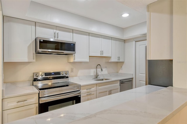 kitchen featuring sink, stainless steel appliances, white cabinets, and light stone countertops