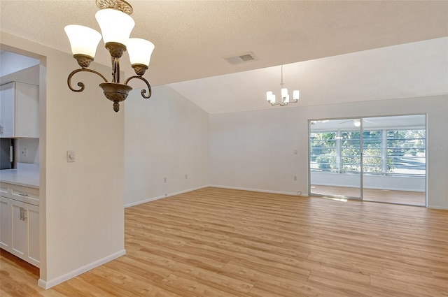 unfurnished living room with lofted ceiling, light hardwood / wood-style flooring, and a textured ceiling