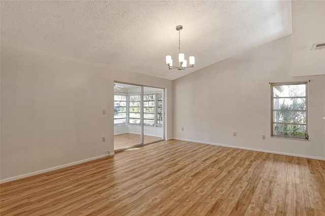 spare room with light hardwood / wood-style floors, vaulted ceiling, a textured ceiling, and a notable chandelier