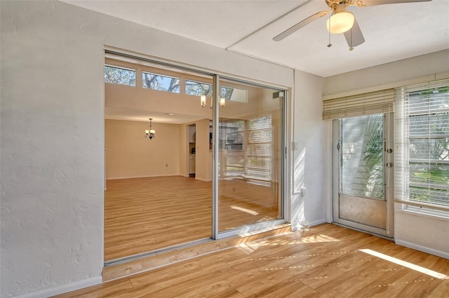 doorway featuring ceiling fan with notable chandelier and hardwood / wood-style floors