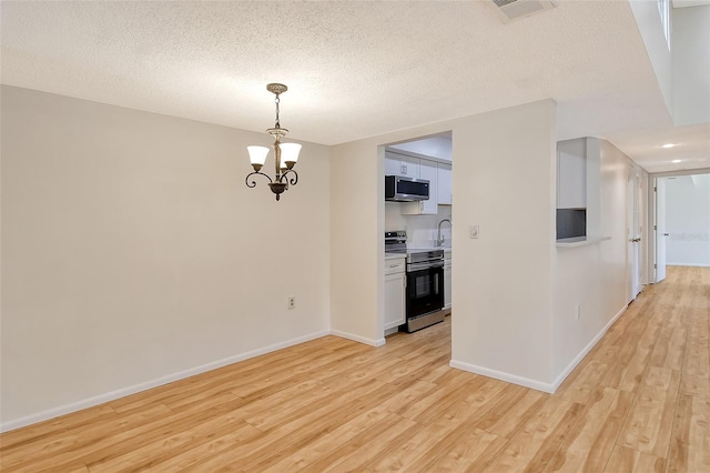 kitchen featuring white cabinetry, hanging light fixtures, light wood-type flooring, a notable chandelier, and stainless steel appliances