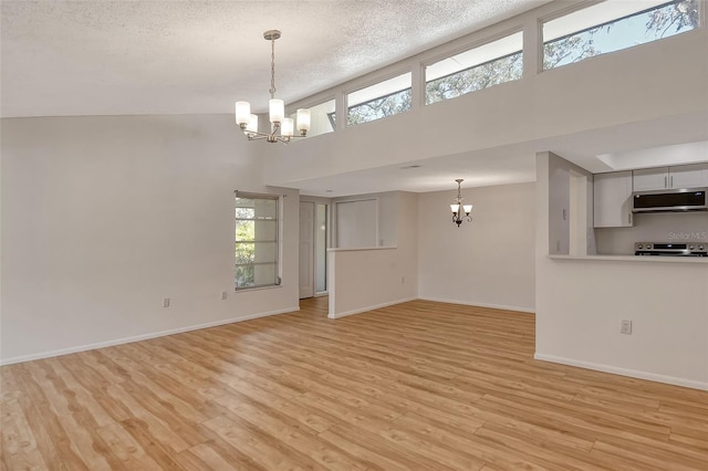 unfurnished living room featuring a notable chandelier, a healthy amount of sunlight, and light wood-type flooring