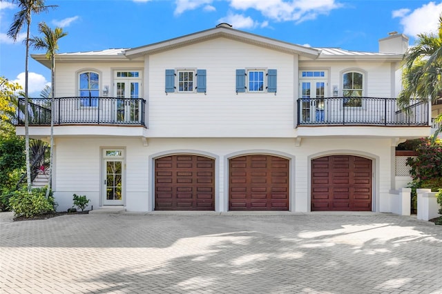 16475 Captiva Dr, Captiva, FL 33924 - view of front of property featuring a balcony, a garage, a chimney, and decorative driveway