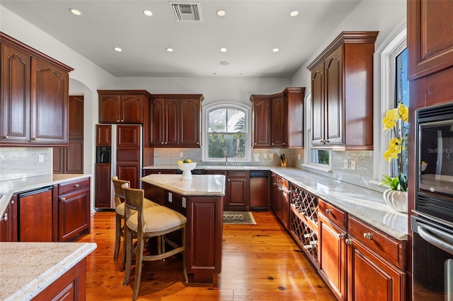 16475 Captiva Dr, Captiva, FL 33924 - kitchen with paneled refrigerator, a kitchen island, light wood-type flooring, recessed lighting, and a breakfast bar