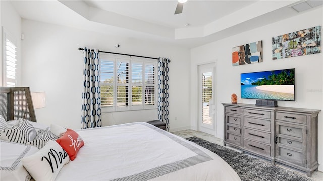 bedroom featuring ceiling fan, access to exterior, and a raised ceiling