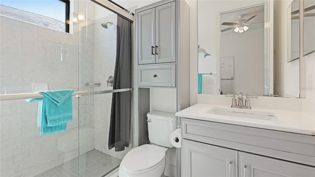 bathroom featuring ceiling fan, vanity, toilet, and a shower with shower door