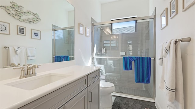 bathroom featuring vanity, a shower with shower door, and toilet