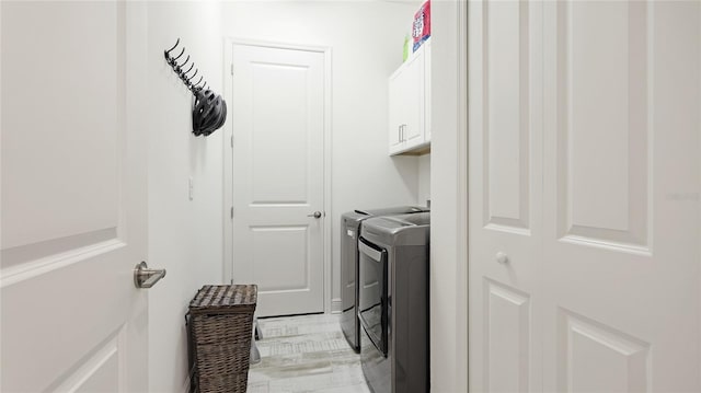 clothes washing area featuring cabinets and separate washer and dryer