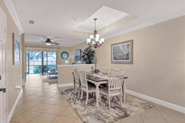 dining room with ornamental molding, ceiling fan with notable chandelier, light tile patterned floors, and a tray ceiling