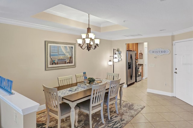 tiled dining space featuring a raised ceiling, crown molding, and an inviting chandelier