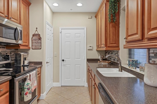 kitchen featuring tasteful backsplash, appliances with stainless steel finishes, sink, and light tile patterned floors