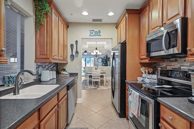 kitchen with sink, appliances with stainless steel finishes, light tile patterned flooring, decorative backsplash, and a chandelier