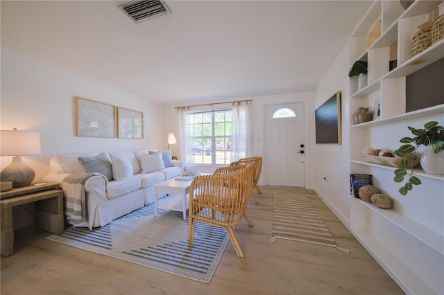 living room with built in features and light hardwood / wood-style floors