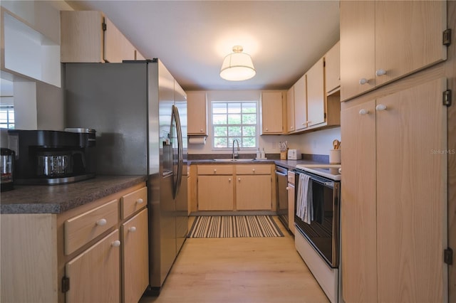 kitchen featuring electric stove, sink, light brown cabinetry, stainless steel dishwasher, and light wood-type flooring