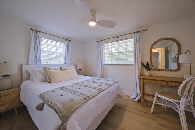 bedroom featuring hardwood / wood-style flooring, ceiling fan, and multiple windows