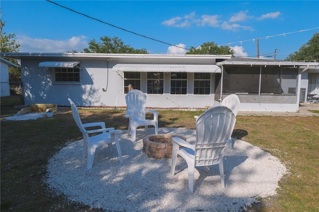 back of property featuring a yard, a fire pit, a patio area, and a sunroom