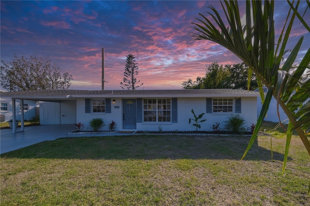 single story home featuring a carport and a lawn