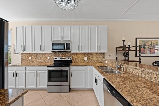 kitchen with sink, appliances with stainless steel finishes, white cabinetry, tasteful backsplash, and dark stone counters