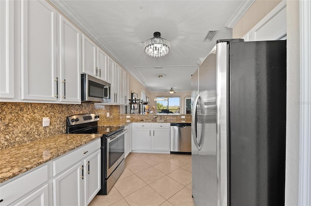 kitchen featuring sink, white cabinetry, light stone counters, light tile patterned floors, and appliances with stainless steel finishes