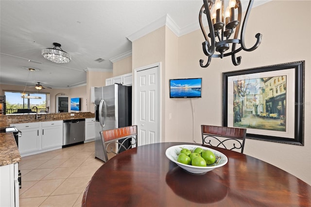 tiled dining space with crown molding, ceiling fan with notable chandelier, and sink