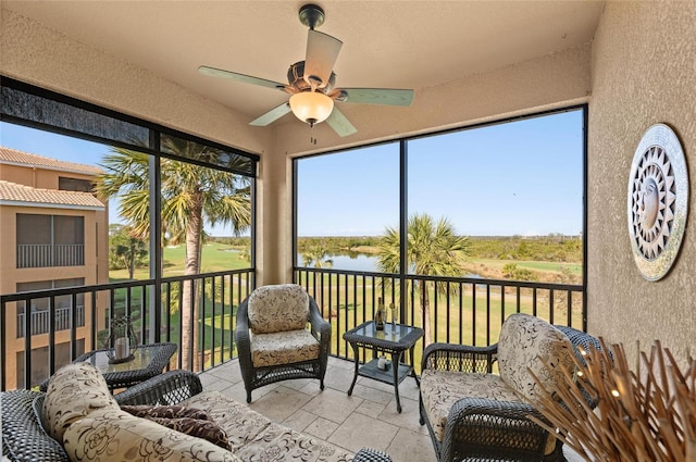 sunroom / solarium with ceiling fan and a water view