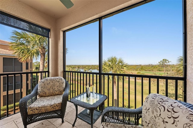 sunroom / solarium featuring ceiling fan and a water view