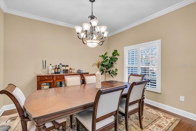 dining room with hardwood / wood-style flooring, crown molding, and a notable chandelier