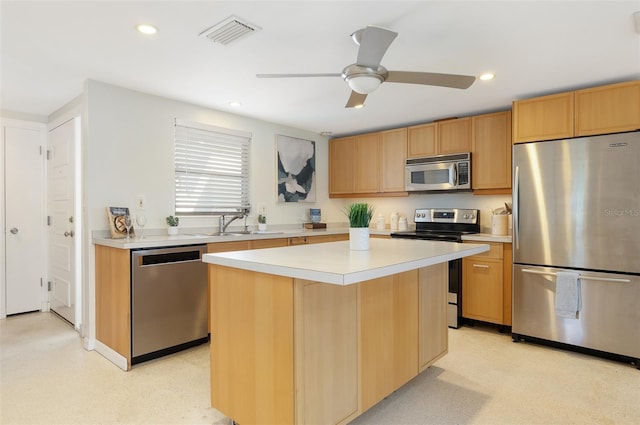 kitchen with stainless steel appliances, a kitchen island, sink, and ceiling fan