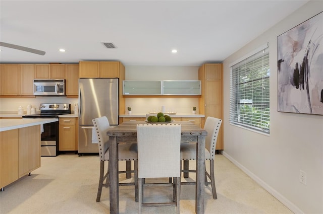 kitchen with stainless steel appliances, a breakfast bar, light carpet, and light brown cabinets