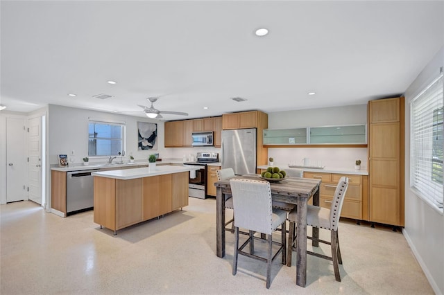 2321 Terry Ln, Sarasota, FL 34231 - kitchen featuring appliances with stainless steel finishes, a center island, light countertops, glass insert cabinets, and recessed lighting