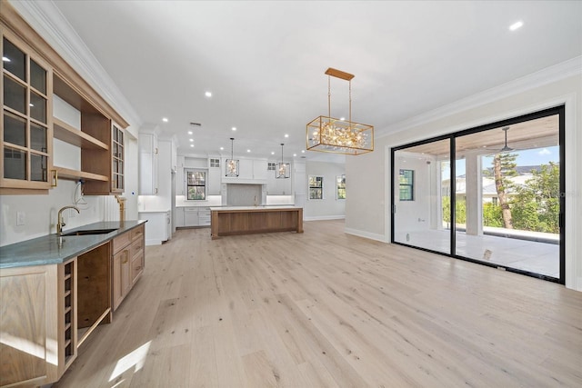 kitchen featuring sink, a center island, hanging light fixtures, light wood-type flooring, and ornamental molding