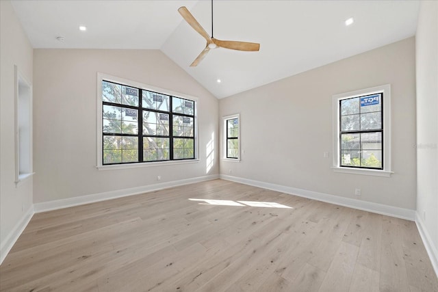 empty room with vaulted ceiling, a healthy amount of sunlight, and light hardwood / wood-style flooring