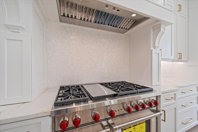656 Tropical Cir, Sarasota, FL 34242 - kitchen with stainless steel stove, white cabinetry, custom exhaust hood, and light stone counters