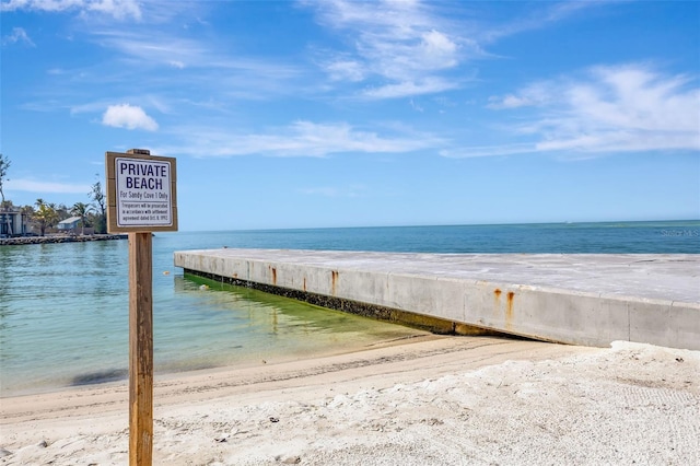 view of dock featuring a water view and a view of the beach