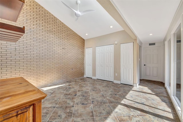 bedroom with multiple closets, brick wall, lofted ceiling, and ceiling fan