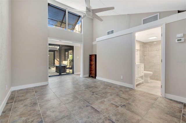 foyer with light tile patterned flooring, ceiling fan, and a towering ceiling