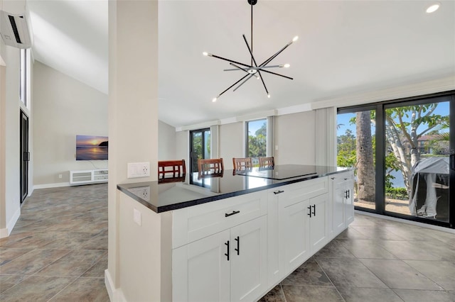 kitchen featuring white cabinetry, black electric cooktop, a wall unit AC, and a wealth of natural light