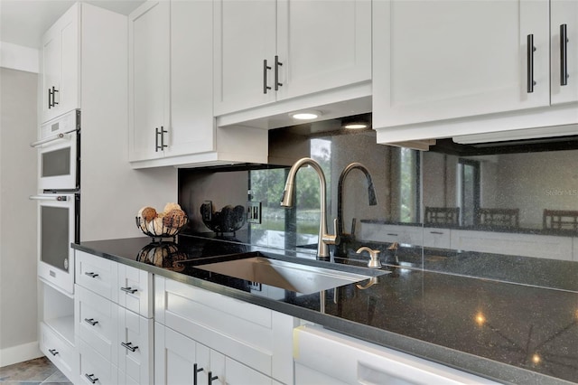 kitchen with sink, white appliances, dark stone counters, and white cabinets