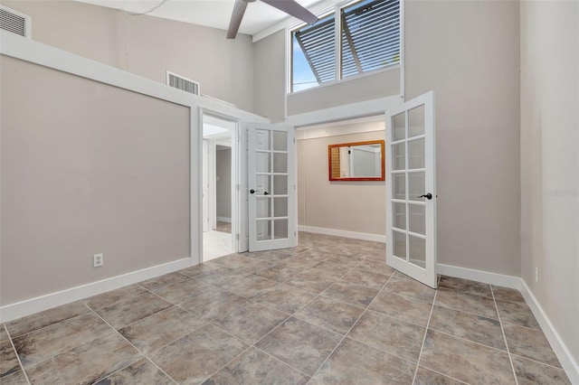 empty room featuring a high ceiling, tile patterned floors, and french doors