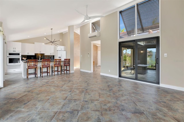 interior space featuring an inviting chandelier, a wall mounted air conditioner, and high vaulted ceiling