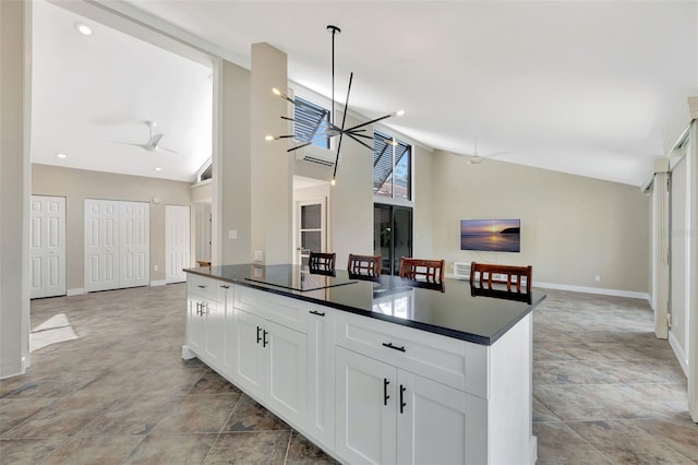 kitchen featuring ceiling fan with notable chandelier, black electric stovetop, high vaulted ceiling, and white cabinets