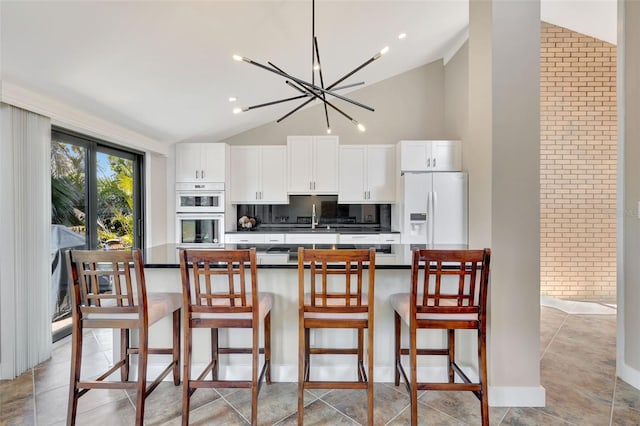 kitchen with a breakfast bar, sink, white cabinets, and white appliances