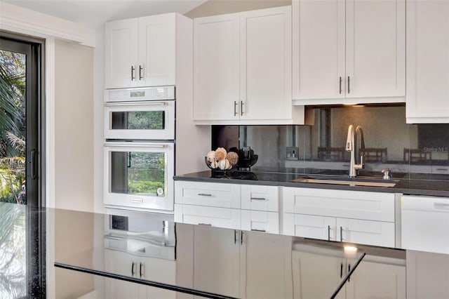 kitchen featuring white cabinetry, sink, white appliances, and tasteful backsplash