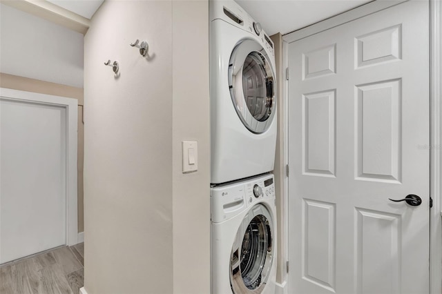 laundry area featuring stacked washer / dryer and light hardwood / wood-style floors